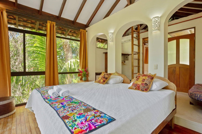 A cabina at Anamaya in Montezuma, with a wide bed and tall windows looking into the jungle