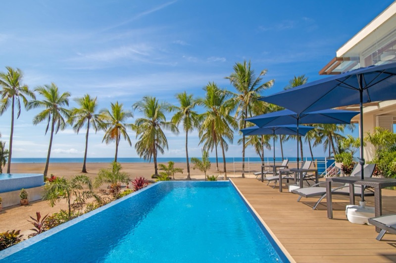 Oceanfront pool and sun deck at Clarita's, with palm trees and the beach at Jacó behind