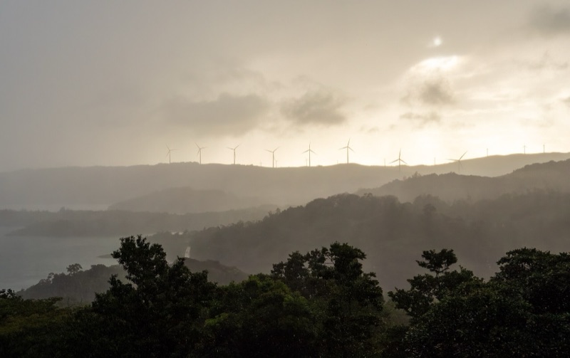 Rain clouds and fog drifting over the hills and wind turbines above Lake Arenal