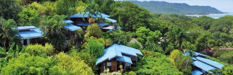 Wooden cabins with blue roofs on the forested hillside above Santa Teresa