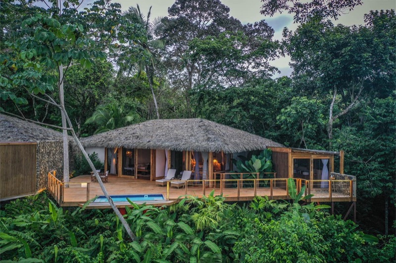 A thatched-roof villa with a deck in the rainforest at Lapa Rios